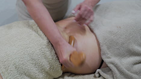 wood therapy massage on the patient's belly with a shaping board