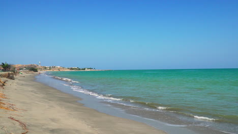 The-tides-of-the-blue-and-green-emerald-sea-are-coming-to-the-shores-of-the-yellow-sands-of-Zorritos-beach-in-Tumbes,-Peru