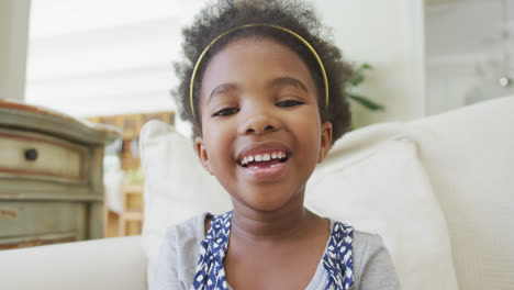 portrait of smiling african american girl looking at camera in living room