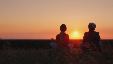 ältere-Frau-Mit-Ihrer-Enkelin-Bewundern-Den-Sonnenuntergang-An-Einem-Malerischen-Ort