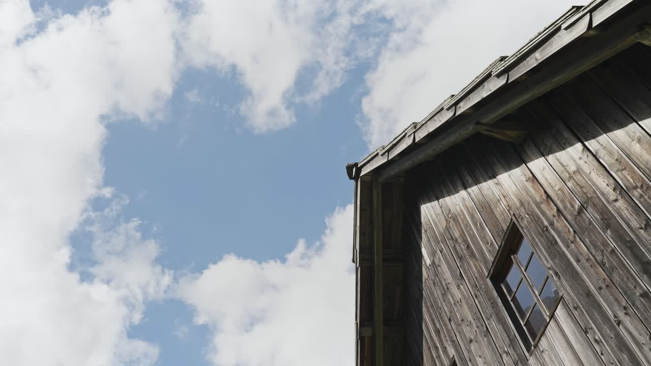 Rustic wooden building with a cloudy sky view in a peaceful countryside setting