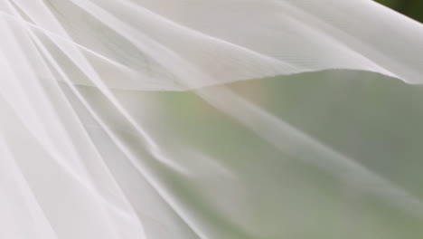 white chiffon fabric waving in wind on green background