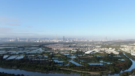 hong kong and shenzhen border line over hong kong rural houses with shenhzen skyline in the horizon, aerial view