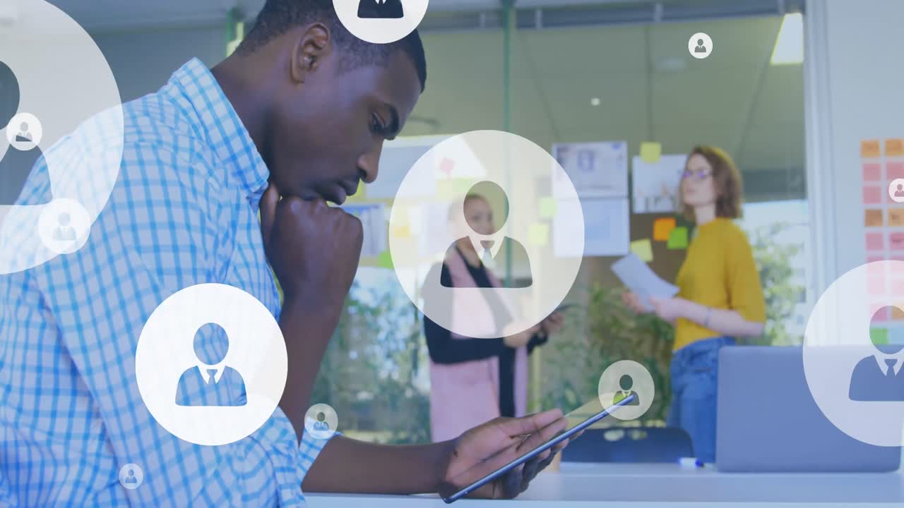 animación de iconos de perfiles contra un hombre afroamericano pensativo que usa una tableta digital en la oficina