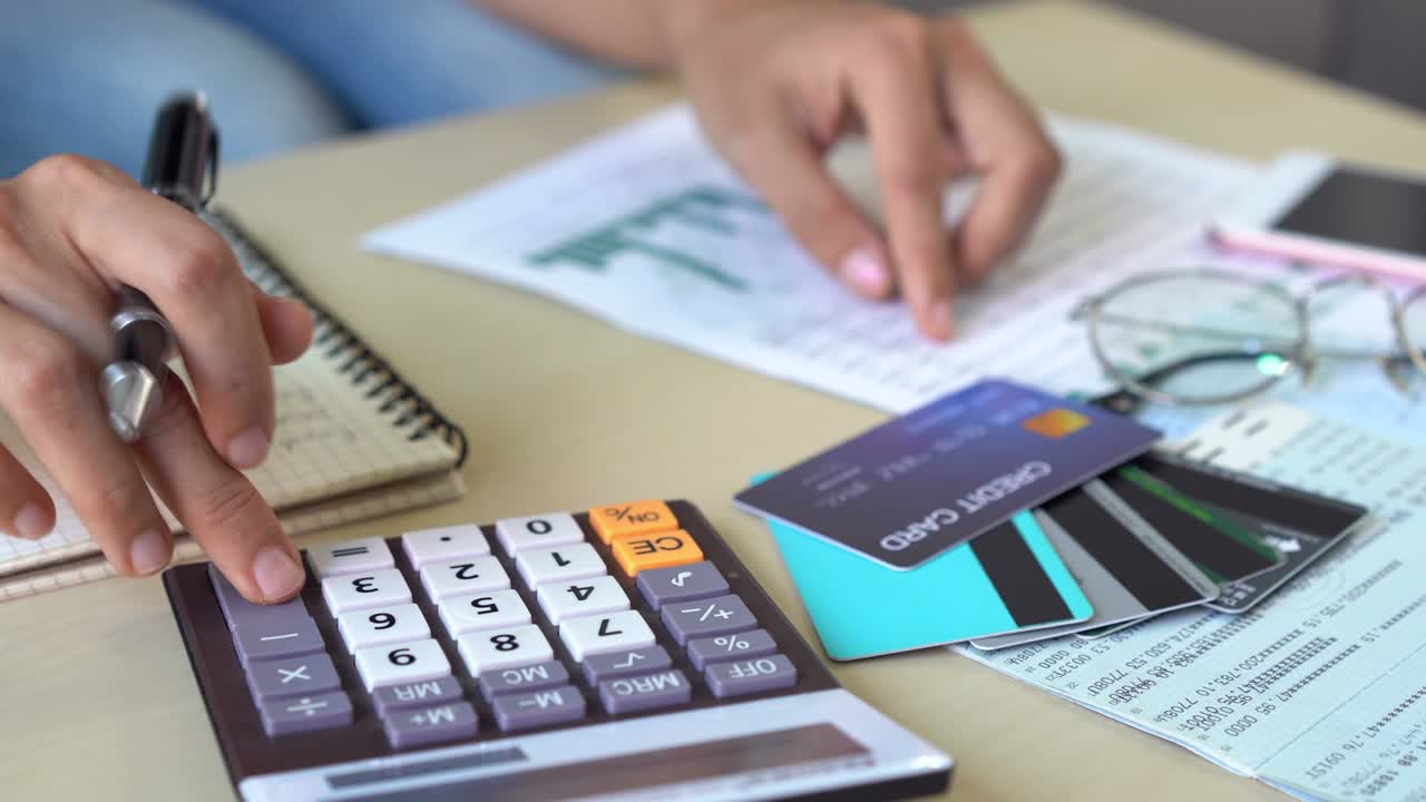 mujer joven comprobando facturas, impuestos, saldo de la cuenta bancaria y calculando los gastos de la tarjeta de crédito en casa