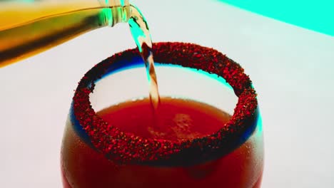 pouring beer into a glass cup with tomato juice