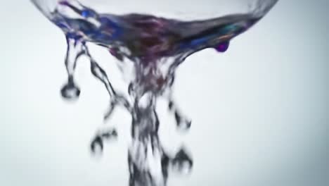 a captivating sequence of fluid dynamics: water pouring gracefully from a translucent vessel, showcasing the dance of splashes and reflections against a minimalist background