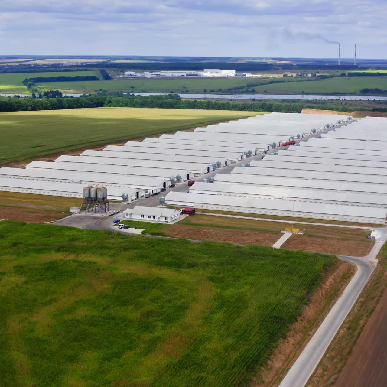 Innovative farm on field in the countryside. Large agricultural area on beautiful green landscape. Harmful factory among nature. Aerial view