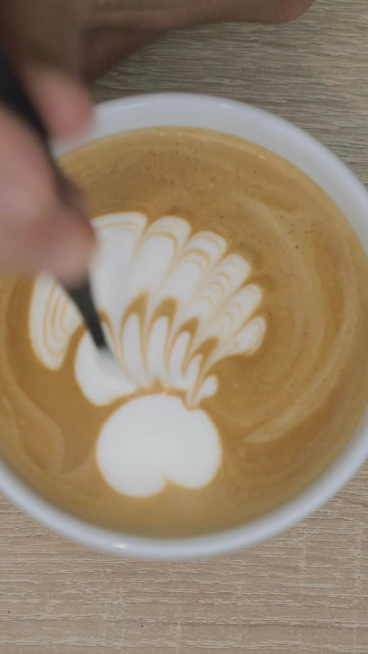 Barista profesional creando arte latte detallado en una taza de café
