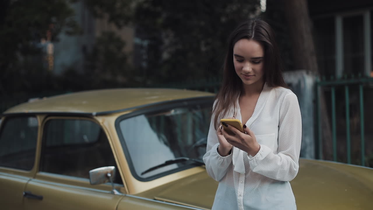Woman using smartphone near car