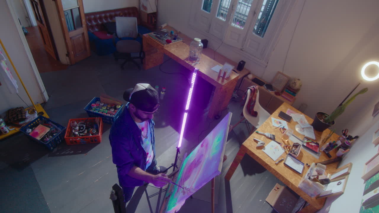 Artist Painting on Canvas with Glow Paint Under UV Light in Studio