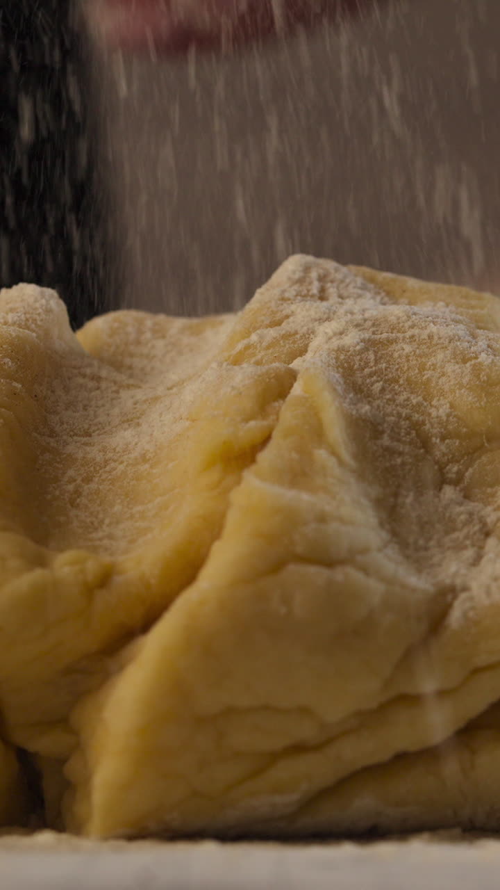 Close-up Of Yellow Dough Being Dusted With White Flour - Cinnamon Roll Making. slow motion, vertical shot