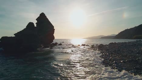 Drone-moving-forward-between-the-rocks-at-the-beach