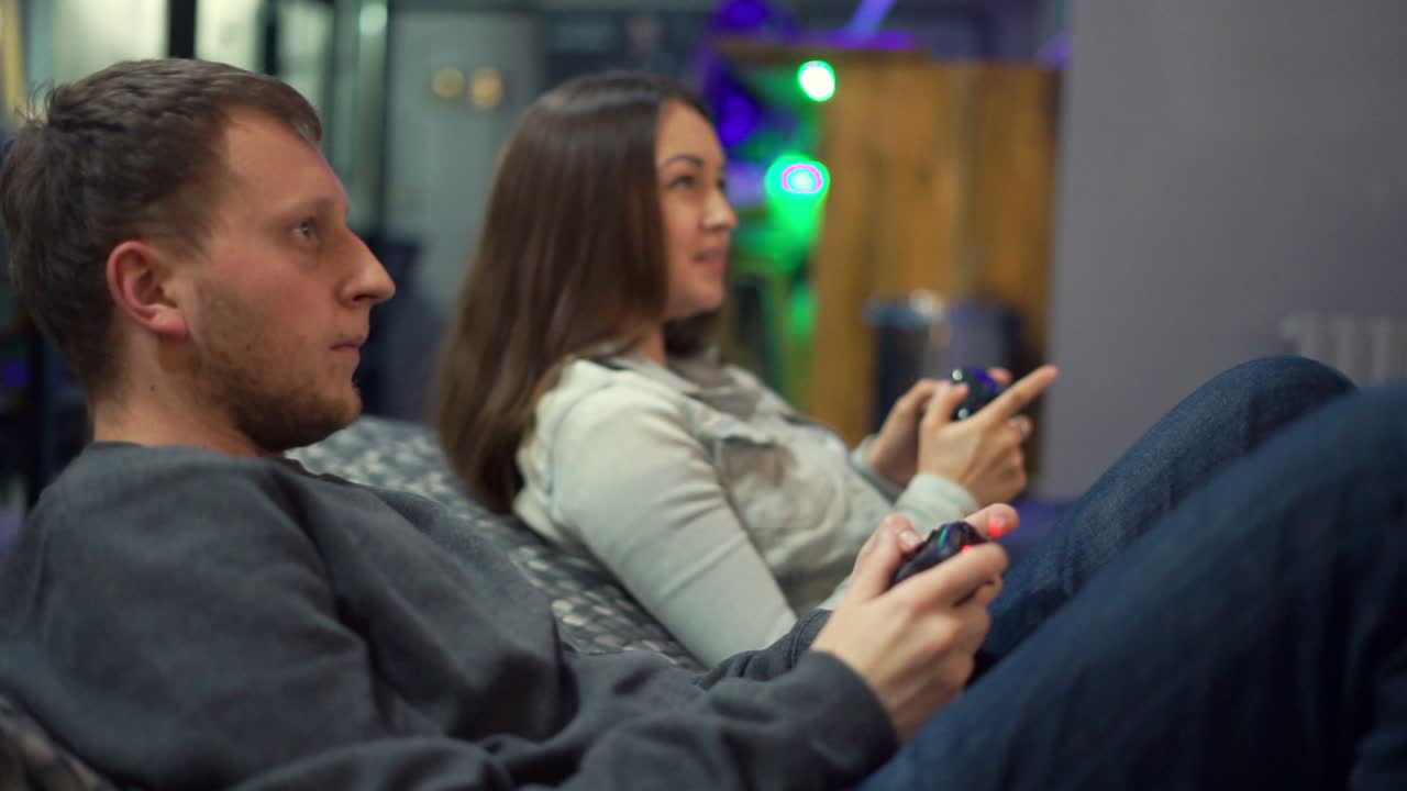 Giovane coppia che gioca ai videogiochi a casa. L'uomo spiega come giocare e usare il controller di gioco. Controller di gioco wireless