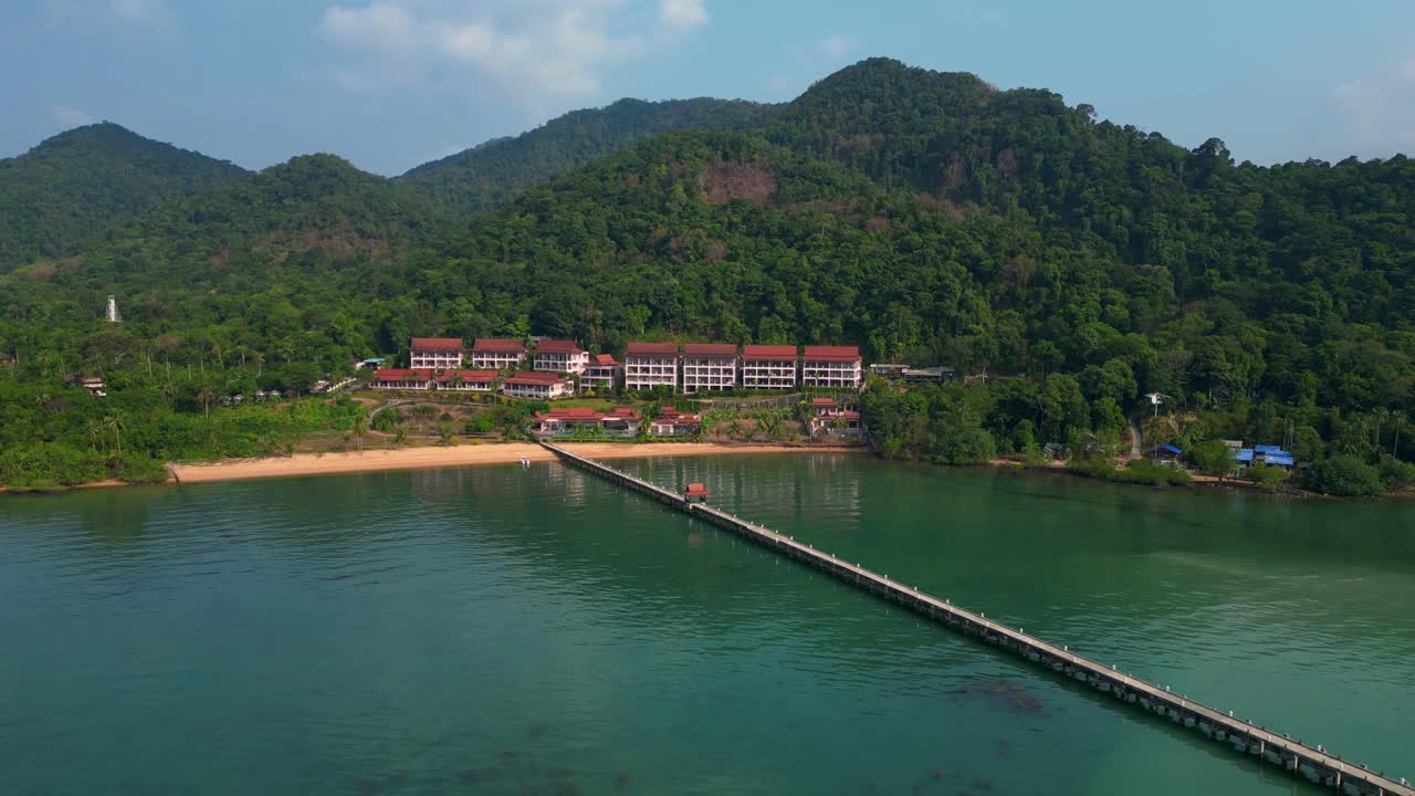 long pier reaching a beautiful resort by the sea in a tropical island koh chang. Marvelous aerial view flight static tripod hovering drone