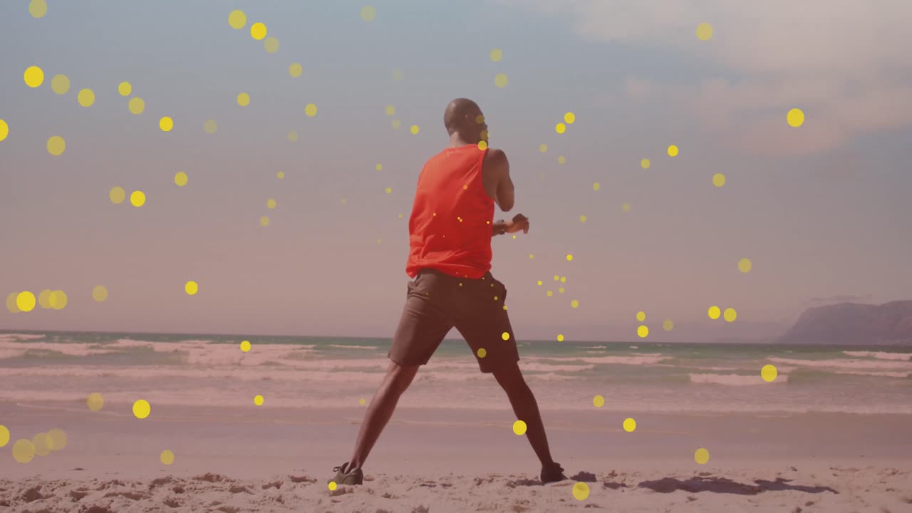 manchas amarillas flotando contra afroamericano hombre en forma realizando ejercicio de estiramiento en la playa