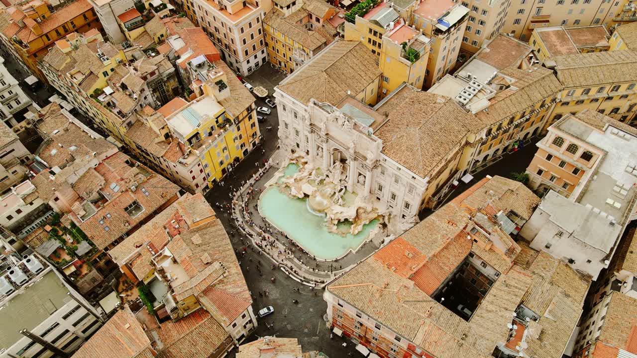 Cinematic top view of famous Trevi Fountain as tourists fill historic square