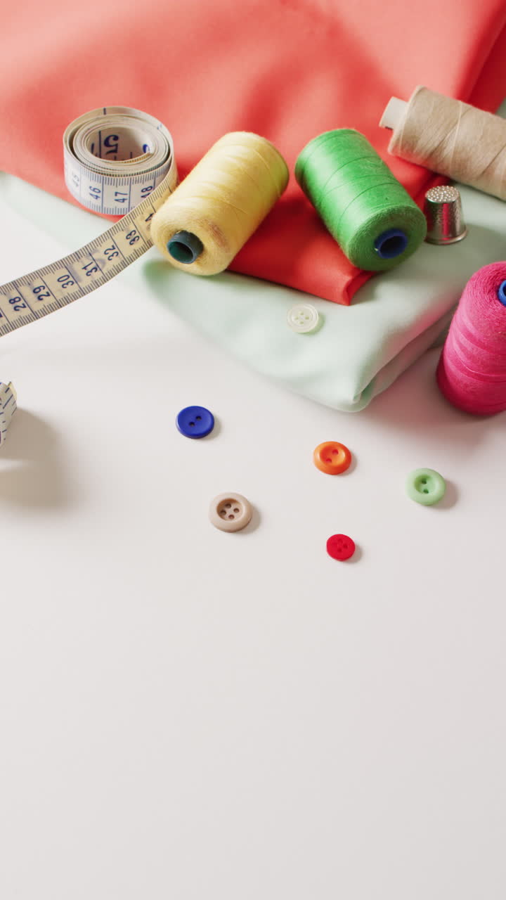 vídeo vertical de tela, botones, cinta métrica y bobinas de algodón sobre fondo blanco con espacio para copiar