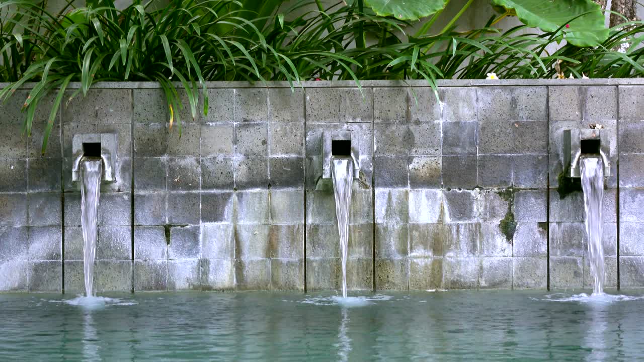 las corrientes de agua están fluyendo hacia la piscina, bali, indonesia