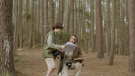 Caucasian-woman-and-her-curious-son-exploring-wildlife-in-pine-forest-on-autumn-day