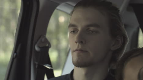 un joven durmiendo en un coche.