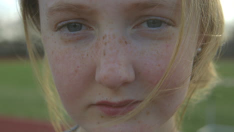 Closeup-of-a-cute-teen-girl-outside-at-a-track-smiling-into-camera