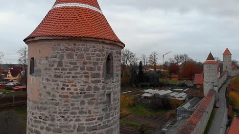 a drone rises slowly past a tower passing near it the wall of the old town and other towers can be seen