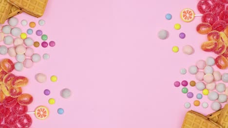 sweet candies appear on left and right side of pastel pink background. stop motion flat lay