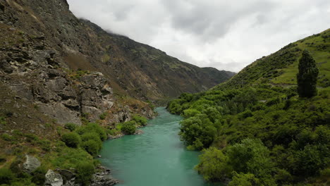 Mountain-valley-and-streaming-blue-river-inside-in-New-Zealand,-aerial-drone-view