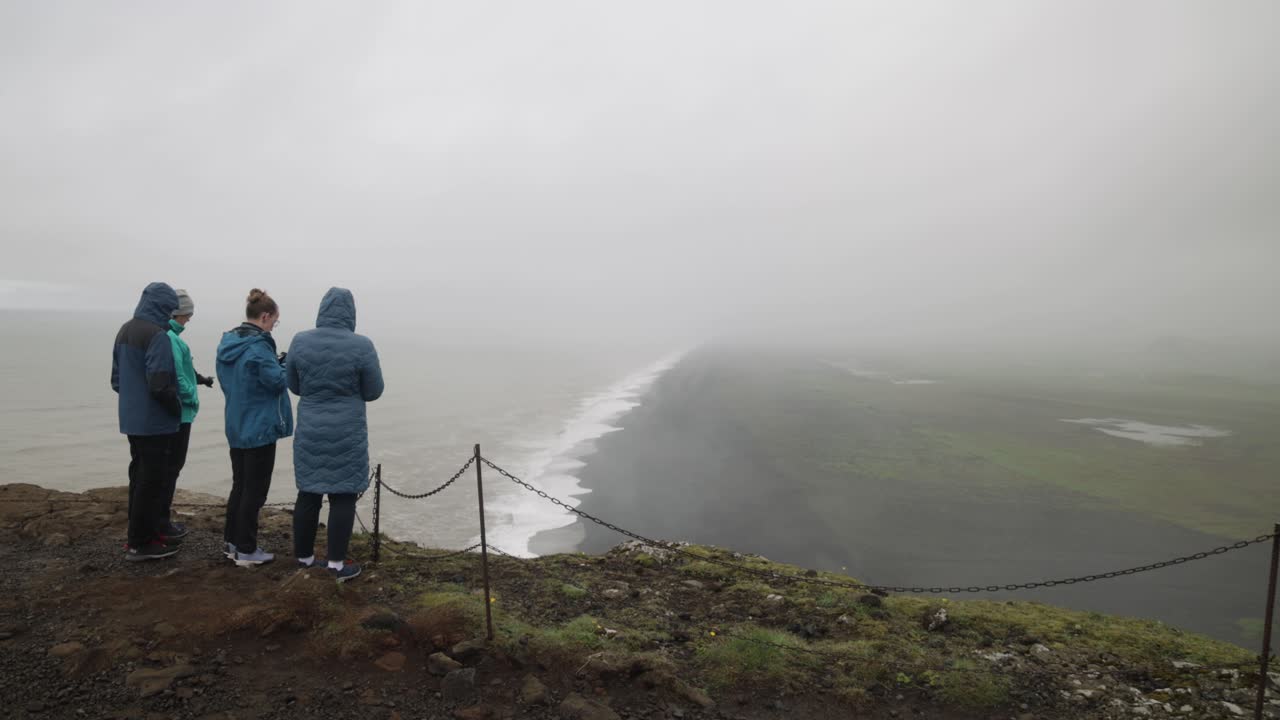 Iceland black sand beach overlook with three people watching.