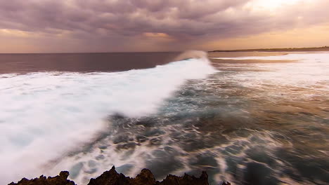 Lapso-De-Tiempo:-Olas-Rodando-Durante-La-Puesta-De-Sol-Con-Desenfoque-De-Movimiento,-Nubes-Malhumoradas-En-El-Cielo