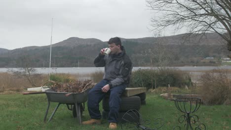 young man taking a break from landscaping work, wide shot