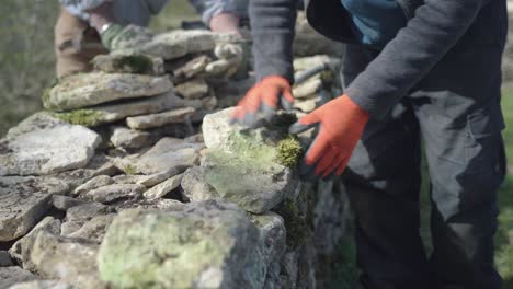 man hands only building dry stone wall, placing stones to make wall