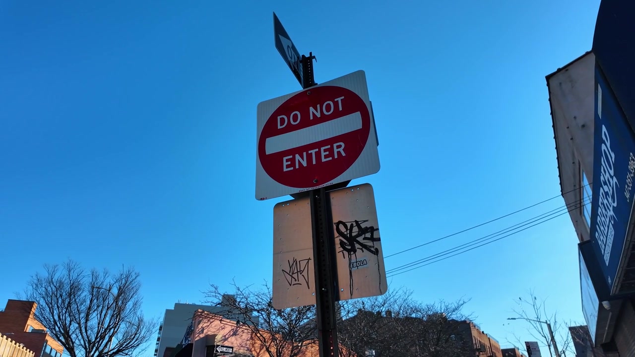 New York, USA, 25 December 2025: Do not enter sign mounted on a city street post, New York City. Red and white signage stands against a clear sky above shops and bare trees.