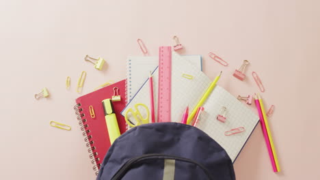 video of backpack with school items on pale pink surface