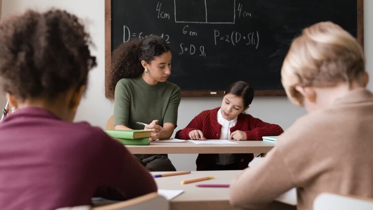Classroom scene of diverse students working with a teacher on math problems