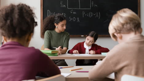 classroom scene of diverse students working with a teacher on math problems