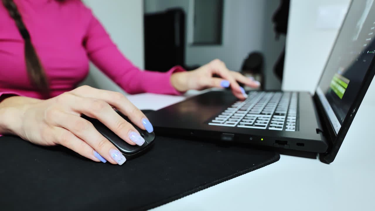 Wide close up of woman in pink sweater editing social content at home desk