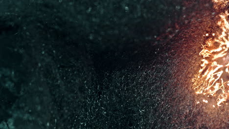 a close-up of a dark, textured surface, as fire burns through it, creating sparks