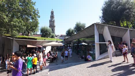 crowd gathers outside famous lello bookstore in porto on a sunny day with the clerigos tower in view