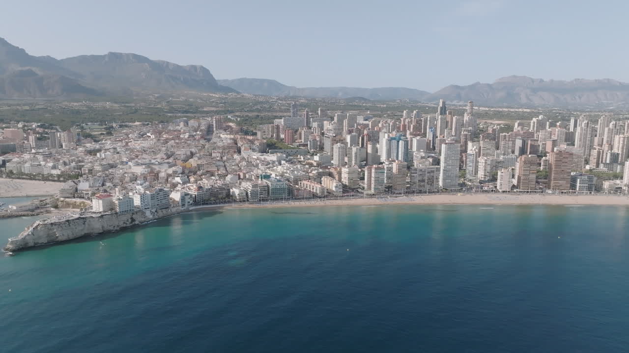 Skyline di Benidorm e spiaggia di Levante in una giornata di sole, con vista sul centro storico e acque cristalline del Mediterraneo.