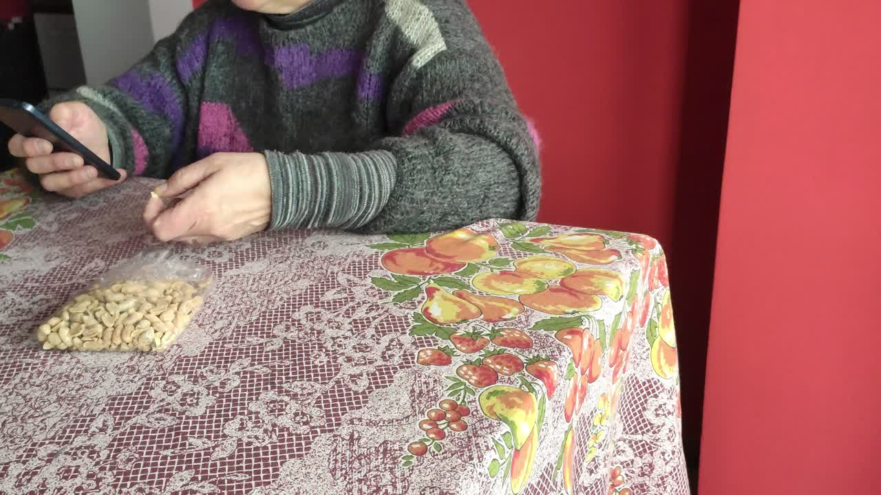 테이블에서 땅콩을 먹고 휴대폰을 사용하는 백인 여성