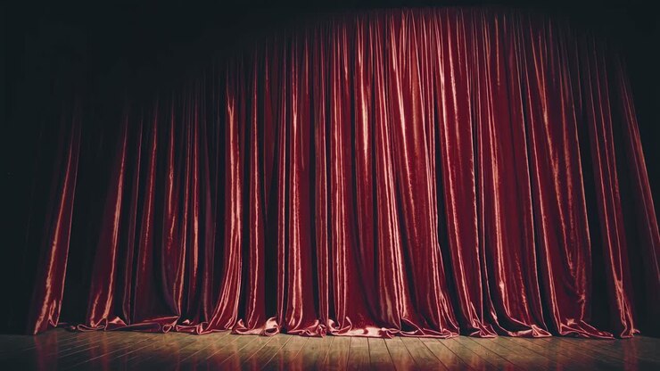 Foto grandangolare di tende rosse di velluto chiuse in un teatro su un palco di legno, che cattura un classico