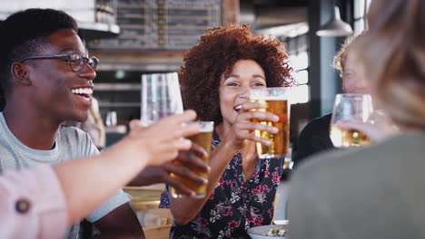 Grupo-De-Jóvenes-Amigos-Reunidos-Para-Tomar-Algo-Y-Comer-Haciendo-Un-Brindis-En-Un-Restaurante