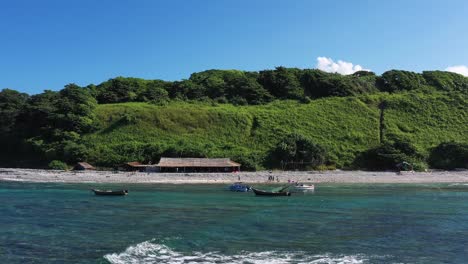 flying drone backward from a beautiful island over the crystal clear water with ocean waves