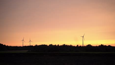 electric windmills spinning in a colorful sunset