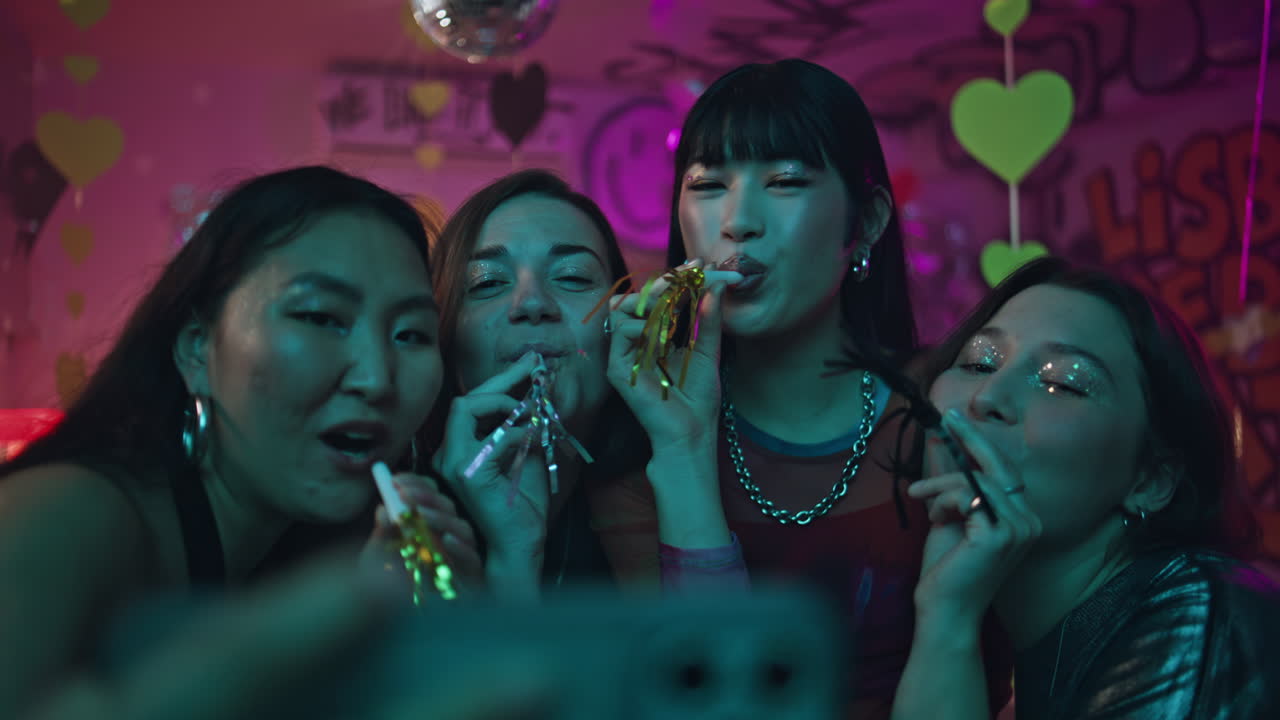 Friends enjoying club party making cellphone selfie at neon backdrop closeup