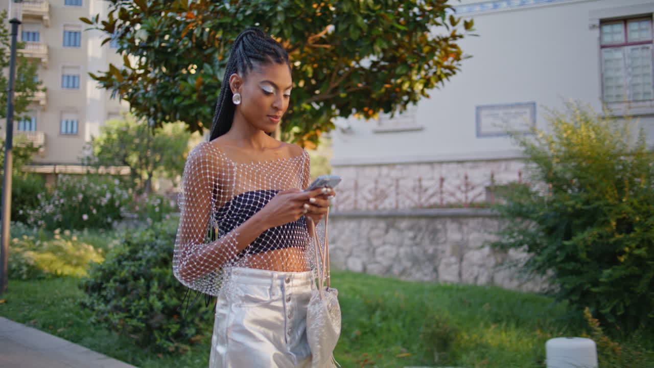 dama feliz navegando dispositivo de teléfono móvil caminando verano centro de la calle primer plano