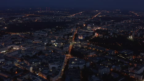 Forwards-fly-above-large-city-at-night.-High-angle-footage-of-illuminated-streets-in-urban-neighbourhood.-Warsaw,-Poland