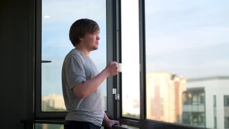 young man drinking coffee at window